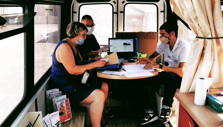 Vue de l'intérieur d'un bus aménagé en France services, avec deux personnes à bord qui consultent l'agent