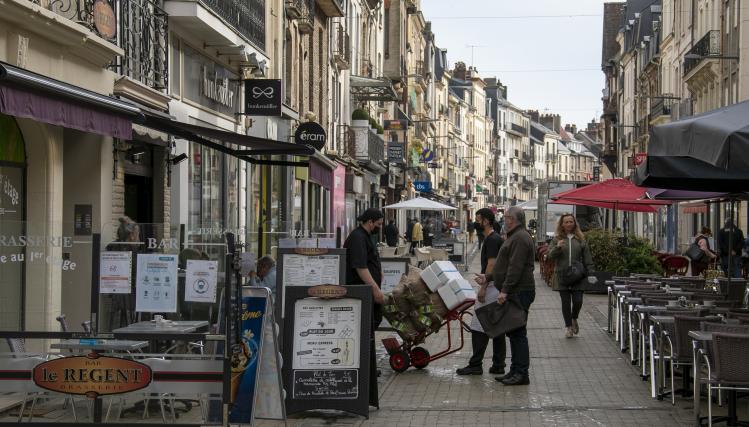 Rue piétonne à Dieppe, avec un restaurateur et son livreur à pied, et une passante. 